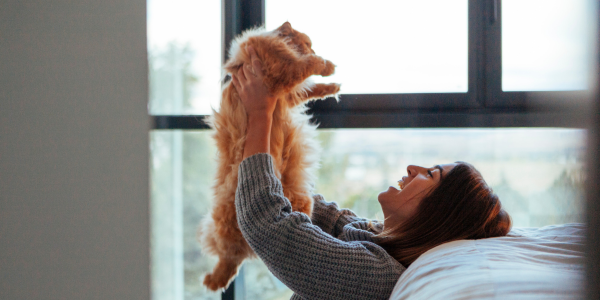 Woman holding a cat in the air